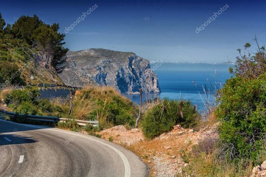 Car driving through a desert landscape with rocky cliffs