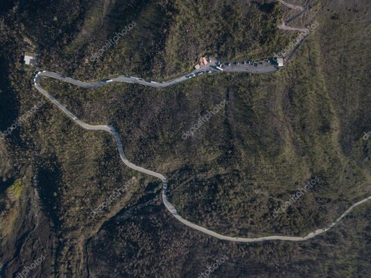 Car on a winding road through green hills